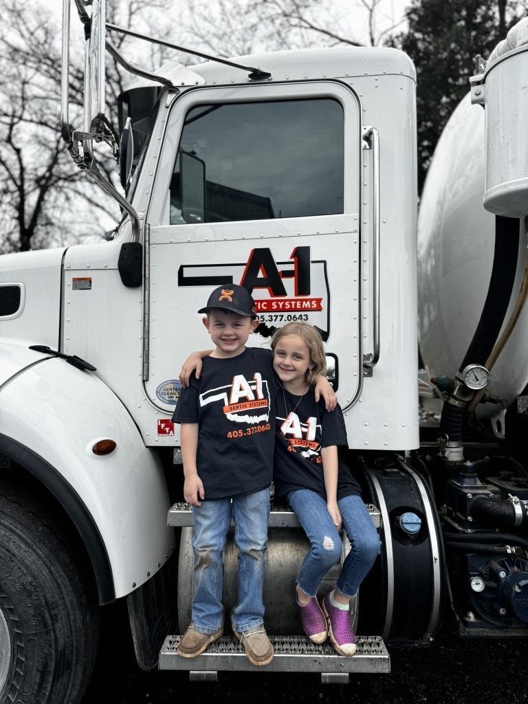 A boy and a girl are sitting on the back of a truck.