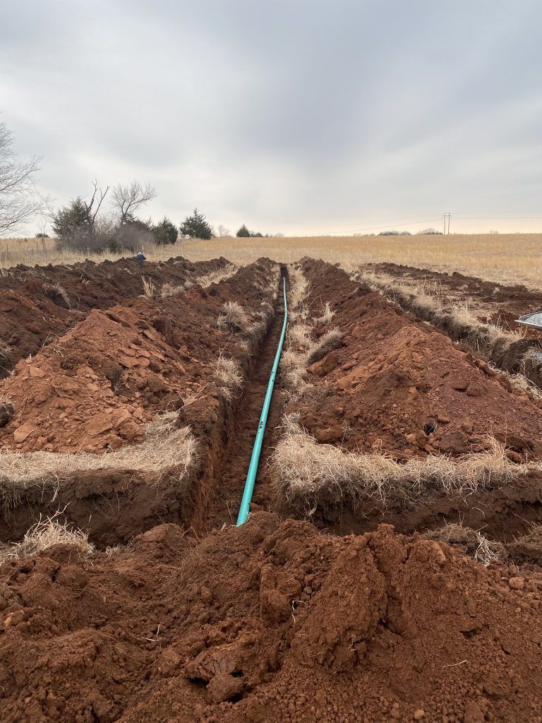 A pipe is being installed in the dirt in a field.