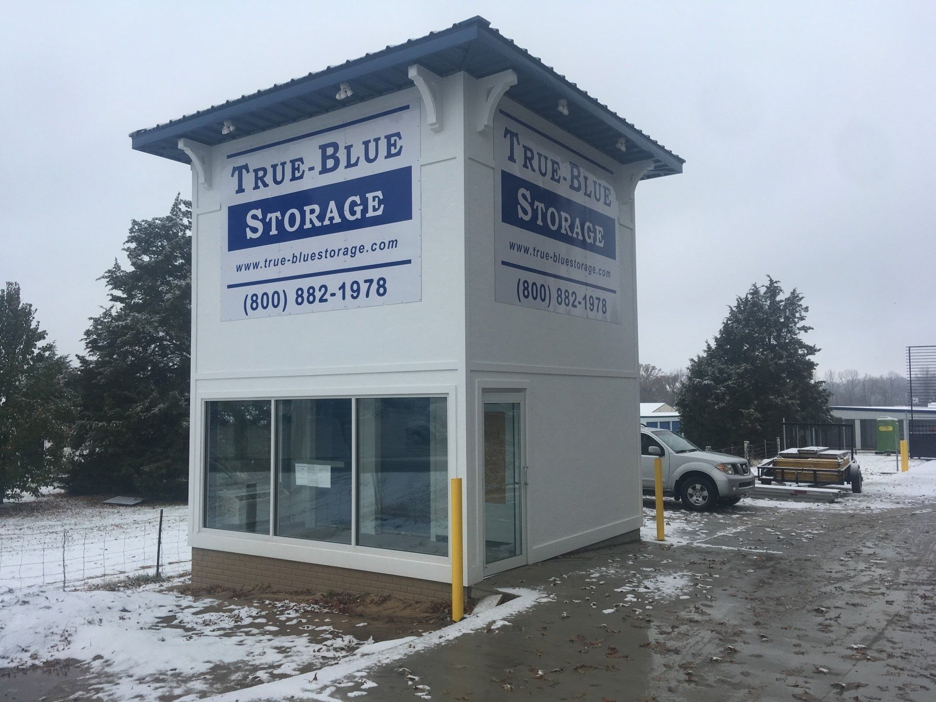True Blue Storage building on a snowy day with a parked car.