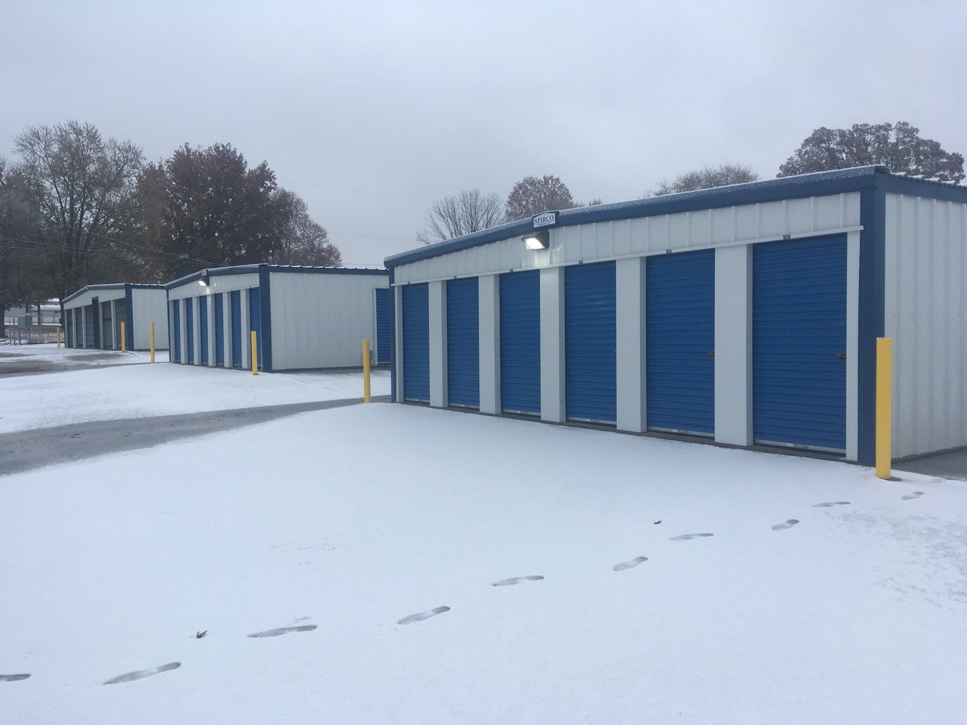 Storage units with blue doors in a snowy outdoor setting.