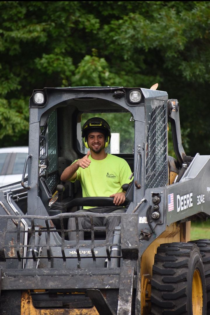 A man is driving a tractor and giving a thumbs up.