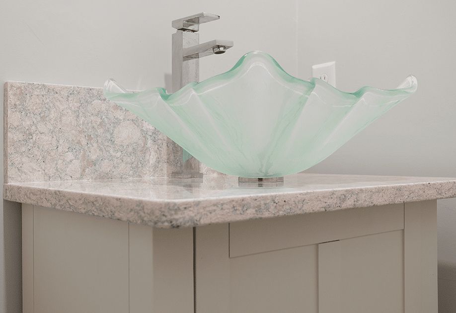 A bathroom sink with a glass bowl on top of it.