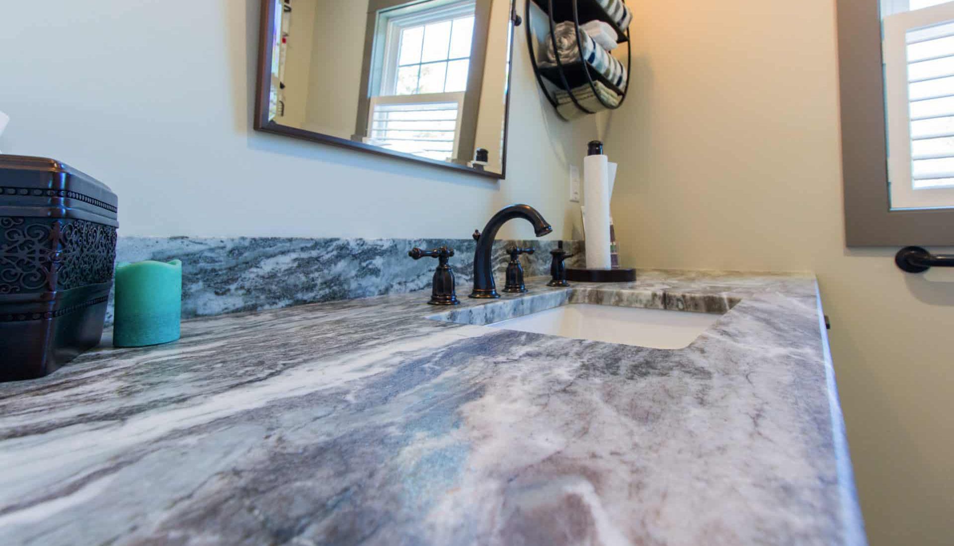 A bathroom with a sink , mirror and candle on the counter.
