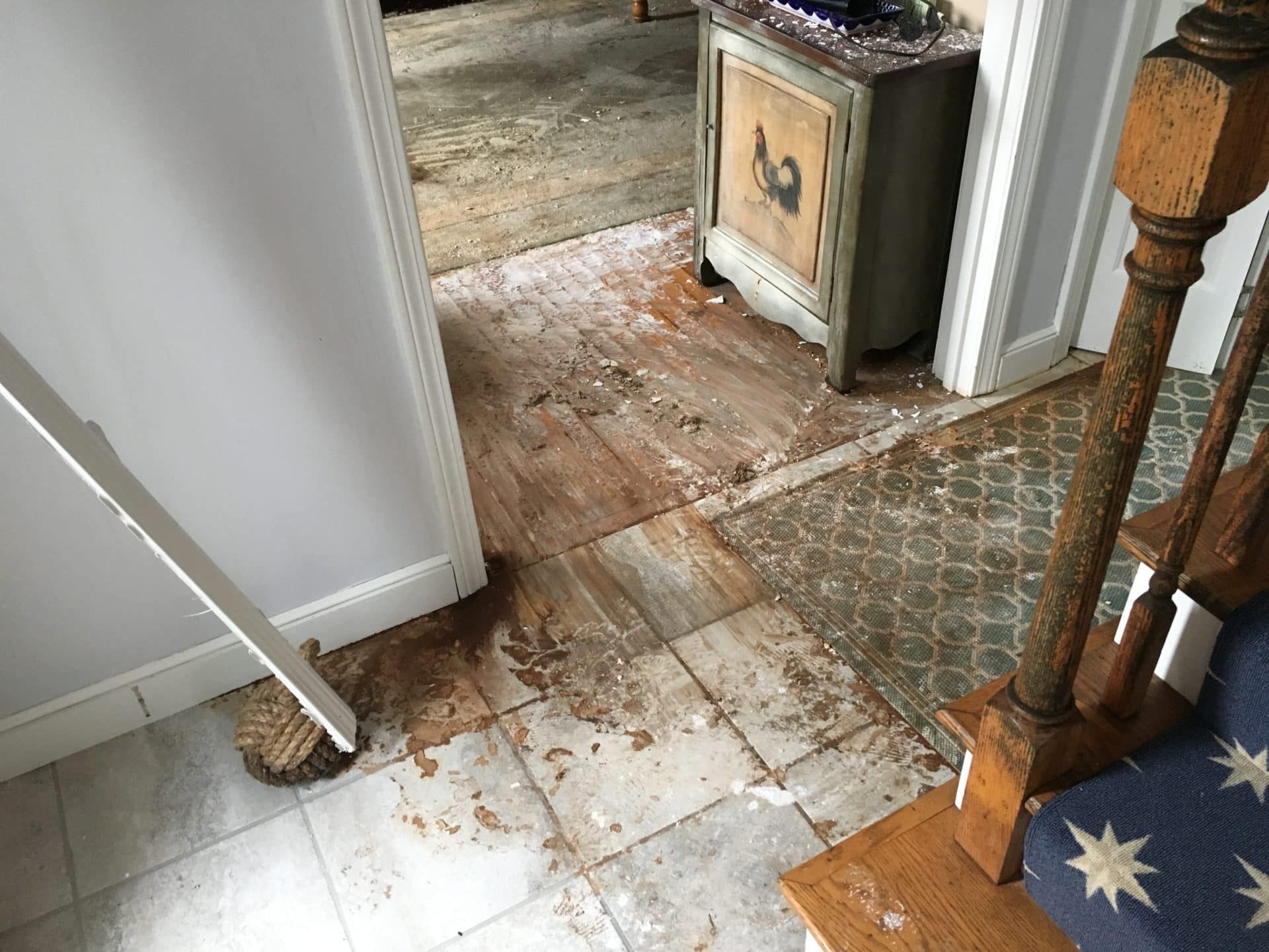 A dirty floor in a room with stairs and a safe.