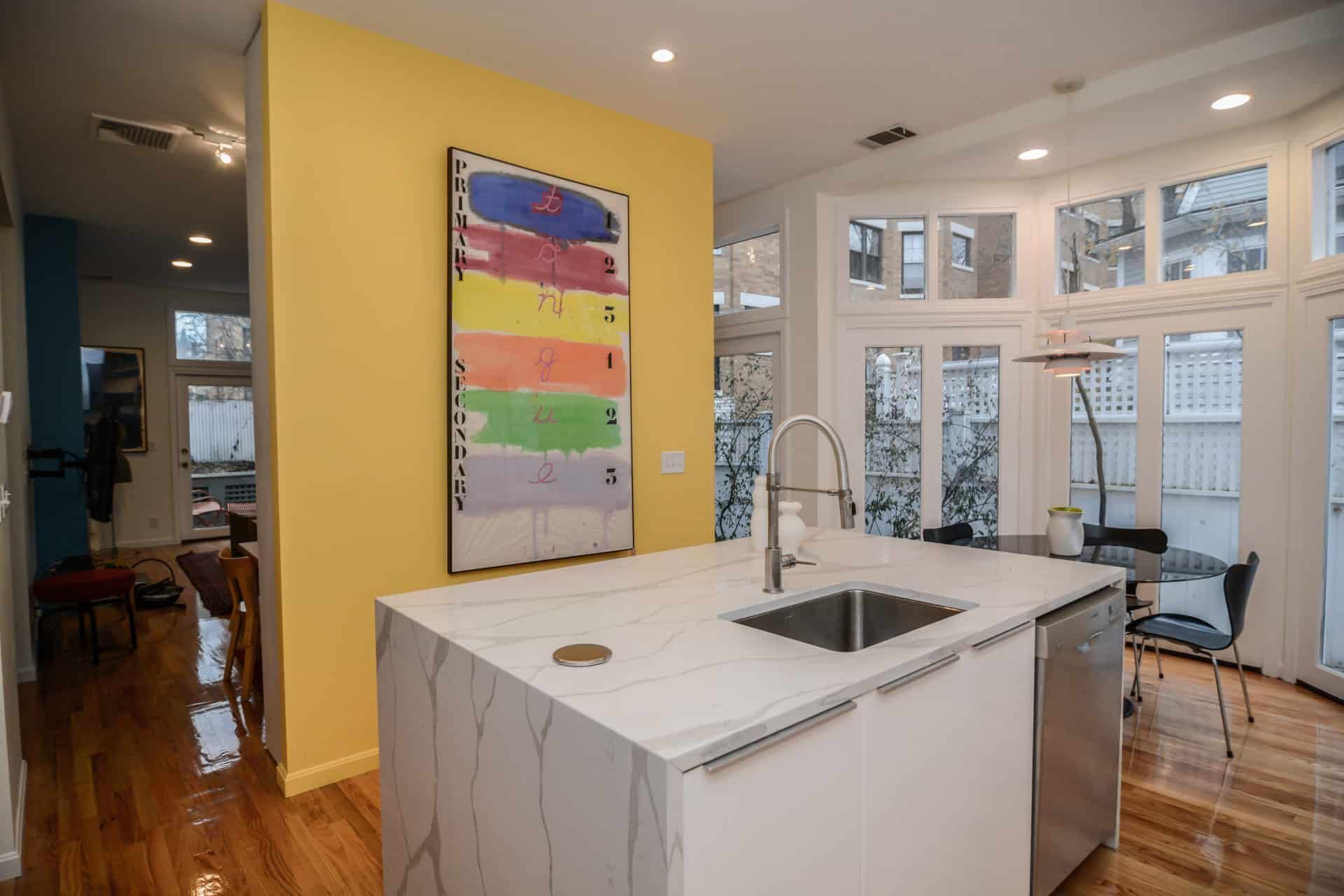 A kitchen with a sink and a painting on the wall.