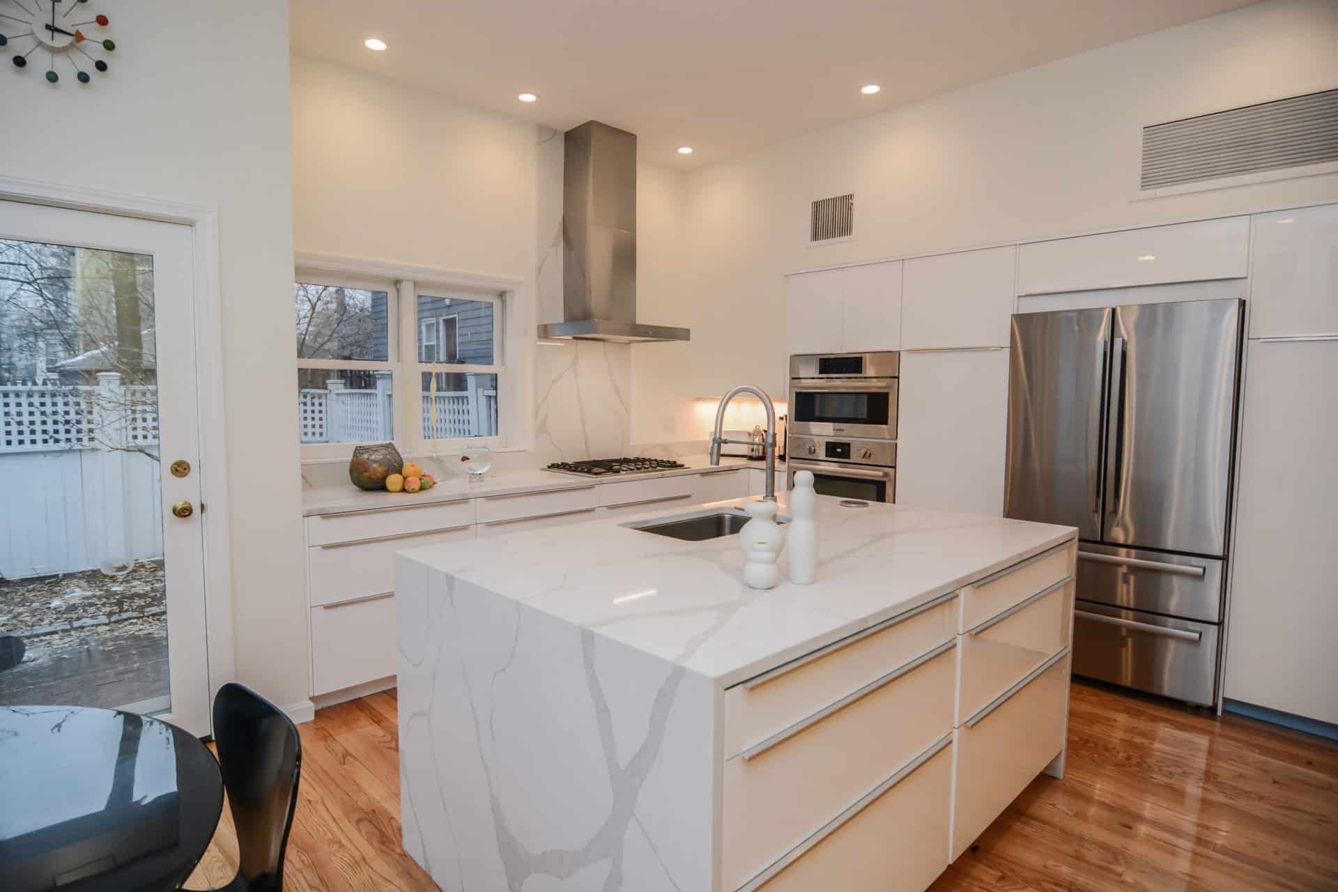 A kitchen with white cabinets and stainless steel appliances and a large island.