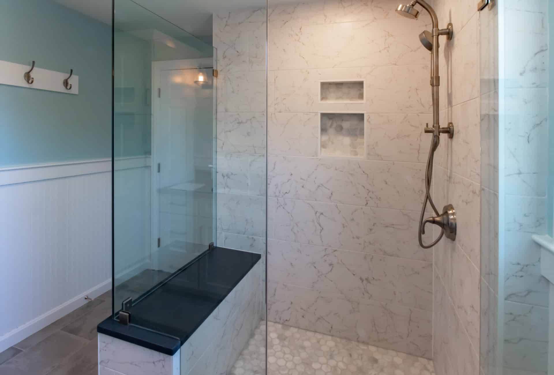 A bathroom with a walk in shower and a bench.