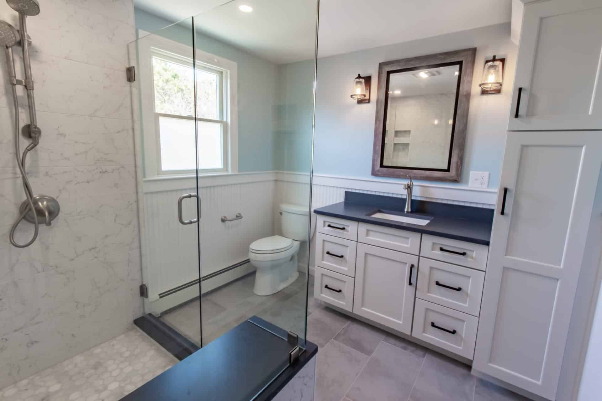 A bathroom with a toilet, sink, shower and mirror.