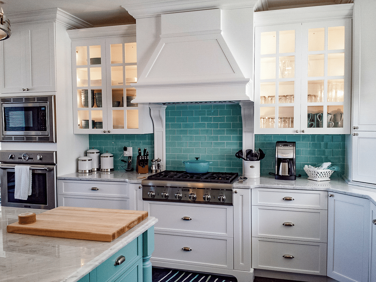A kitchen with white cabinets and blue cabinets and a stove top oven.