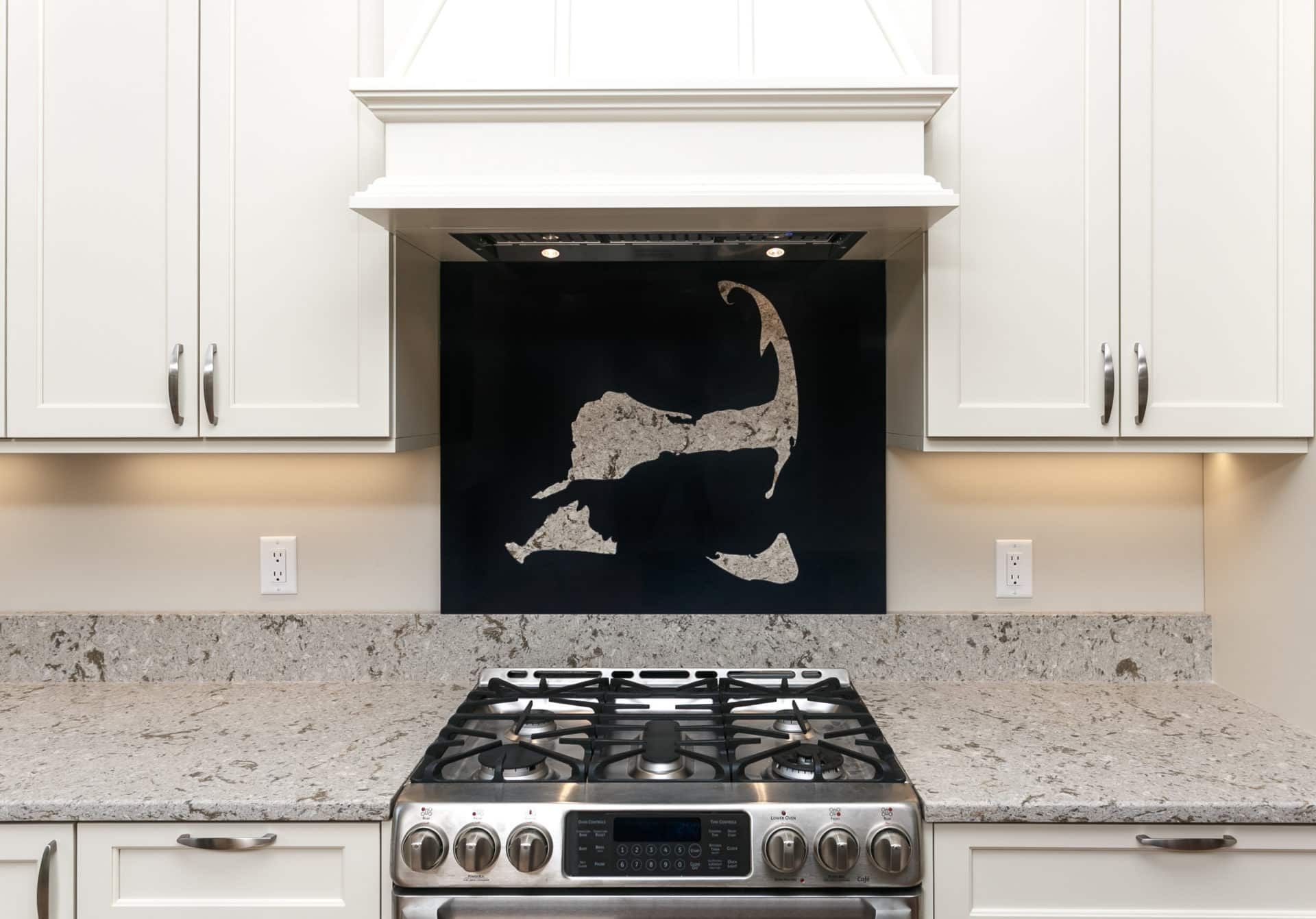 A kitchen with a stove top oven, granite counter tops, and white cabinets.