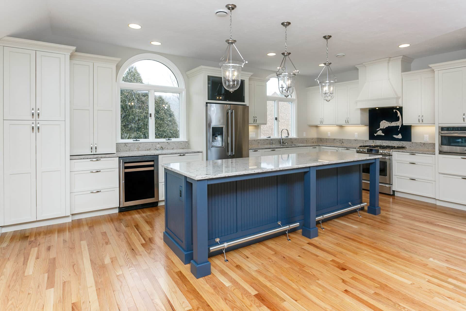A kitchen with white cabinets and a blue island.
