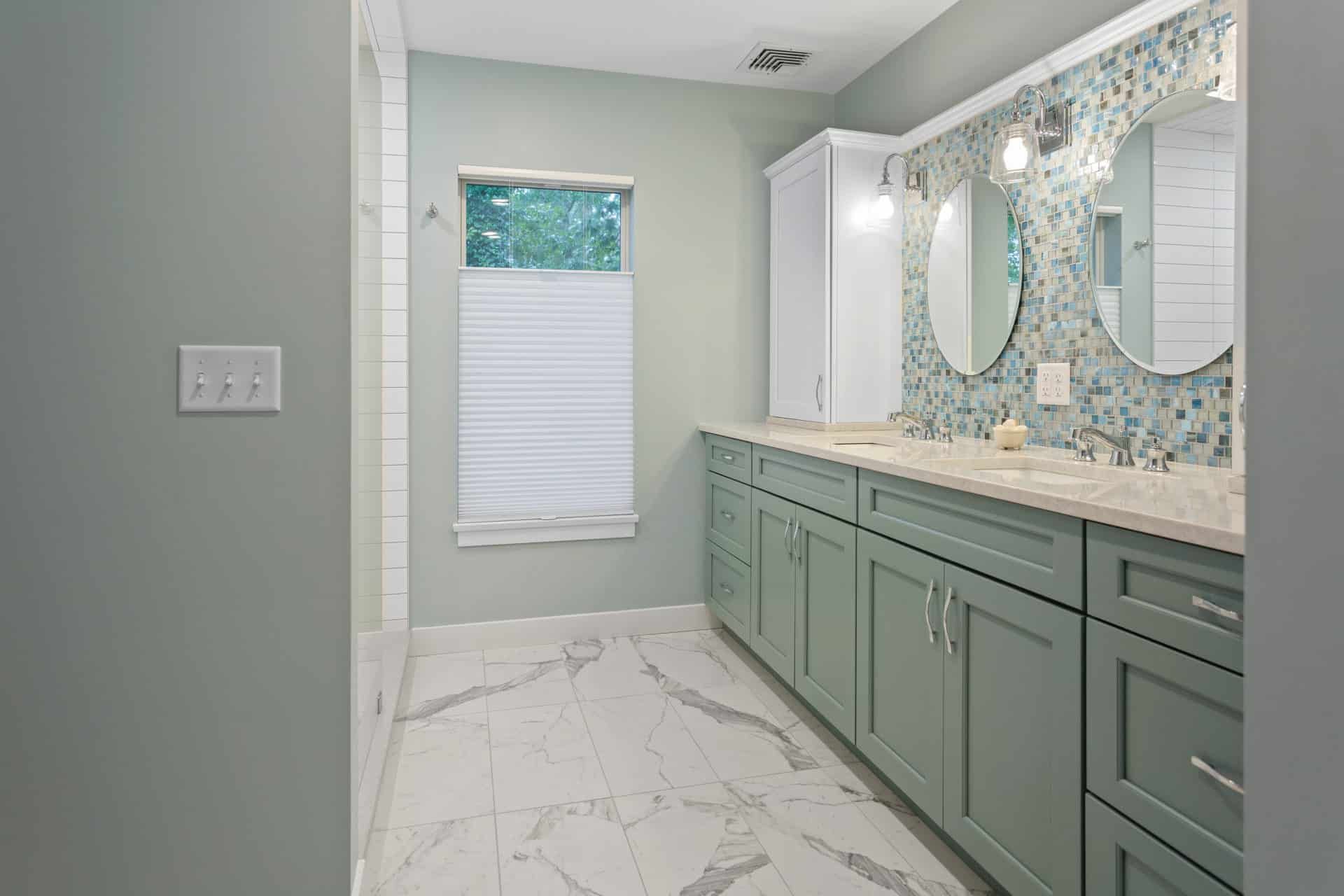 A bathroom with two sinks, two mirrors and a window.