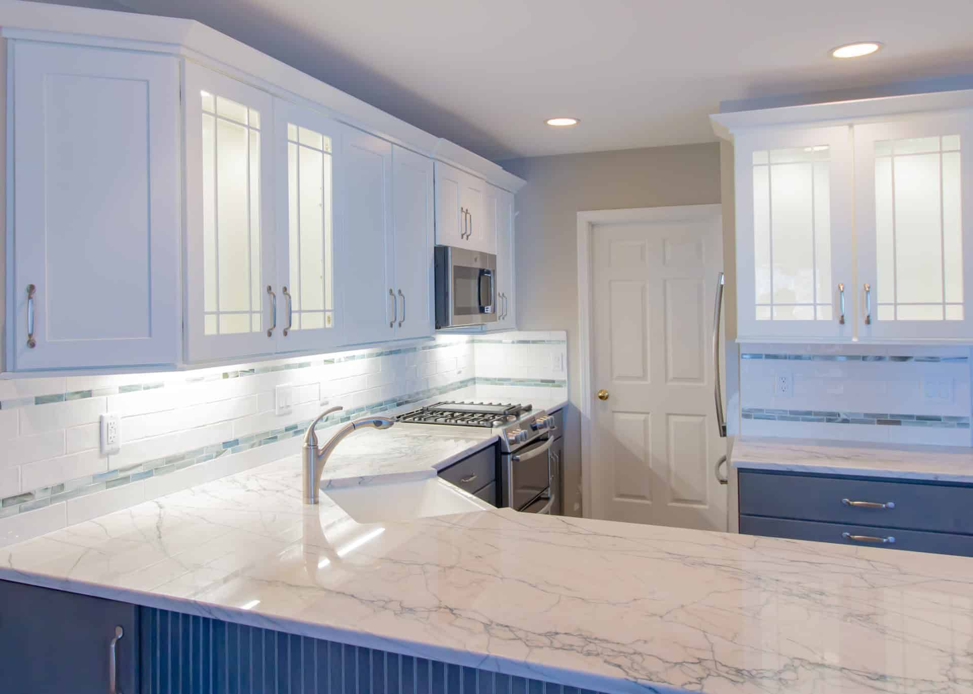 A kitchen with white cabinets, a sink, a stove, and a microwave.