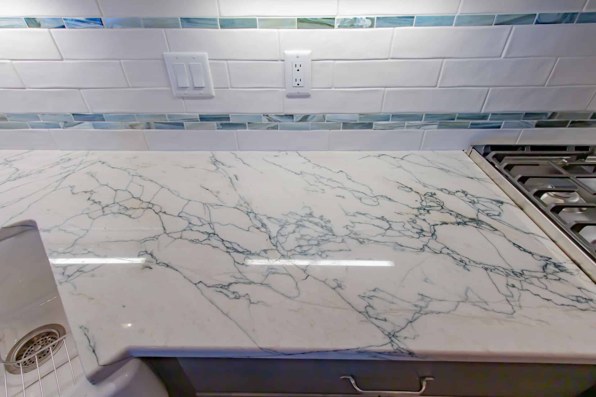 A kitchen with a marble counter top and a stove top oven.