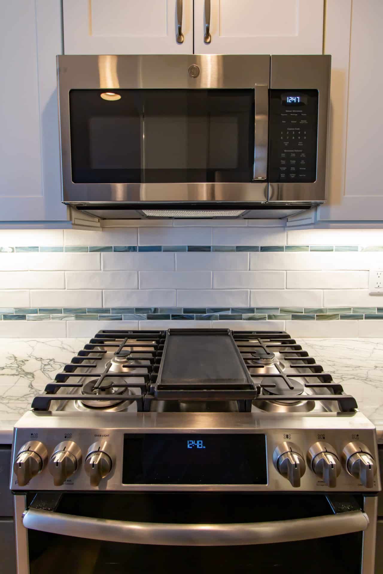 A stove top oven with a microwave above it in a kitchen.