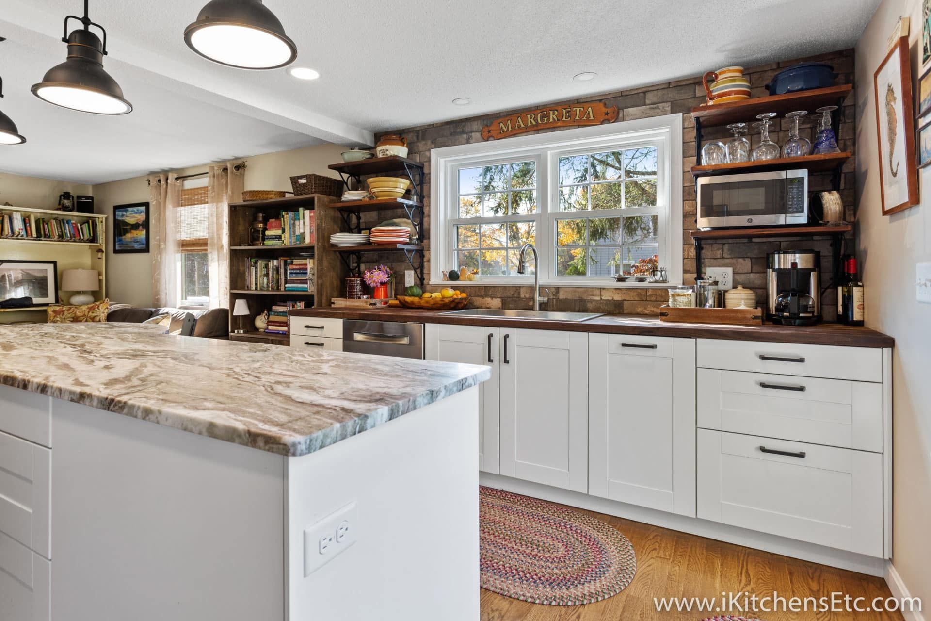 A kitchen with white cabinets, granite counter tops, and a large island.