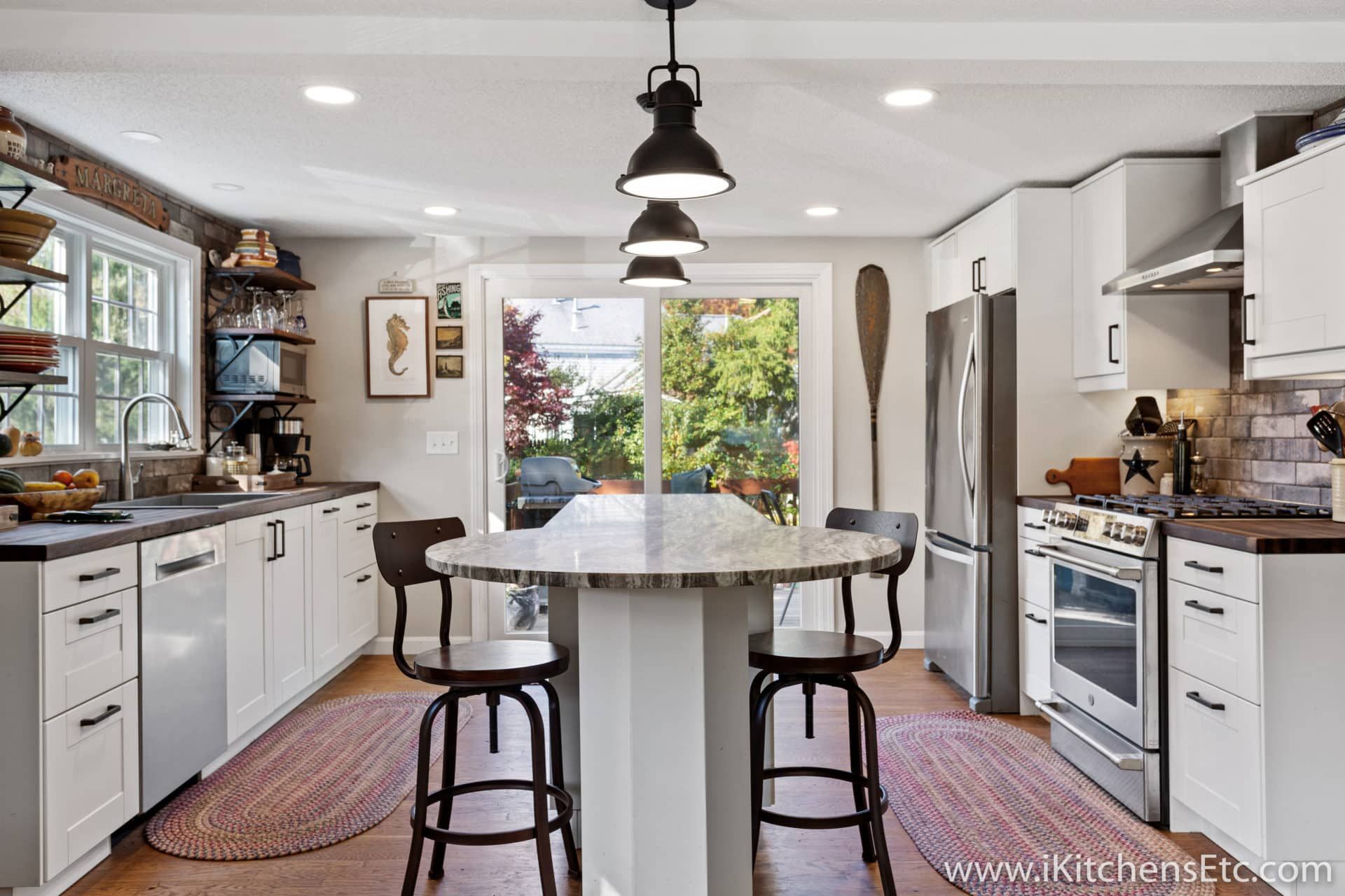 A kitchen with white cabinets, stainless steel appliances, a large island with a table and chairs.