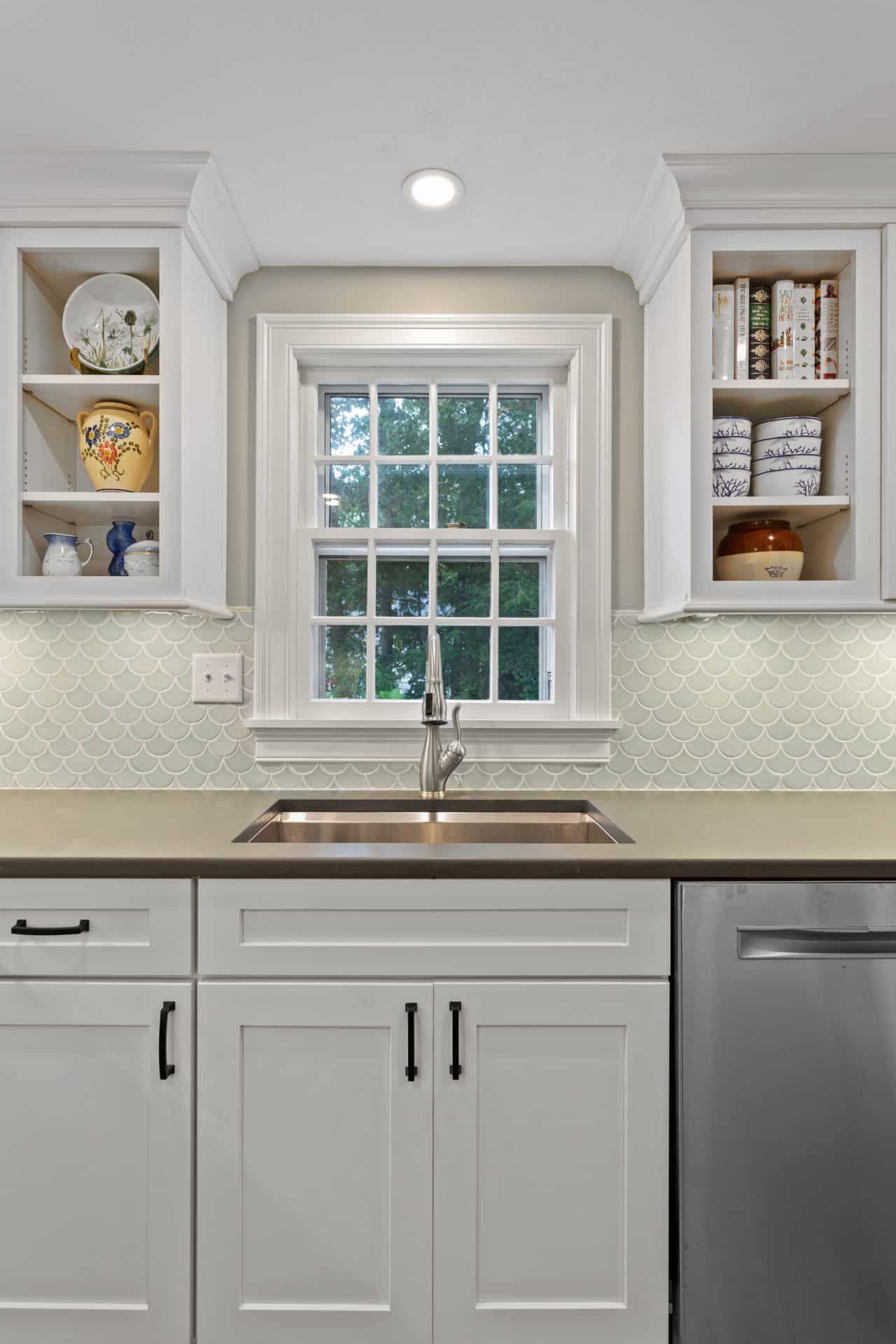 A kitchen with white cabinets, a sink, and a window.