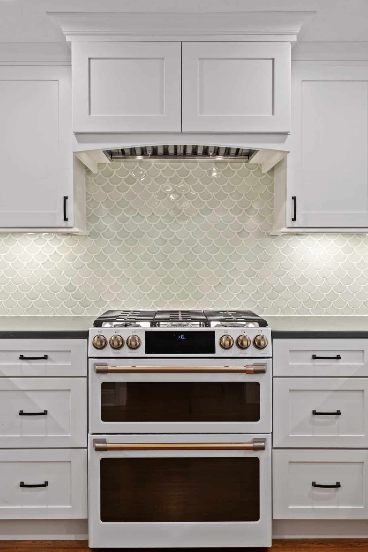 A kitchen with white cabinets and a white stove top oven