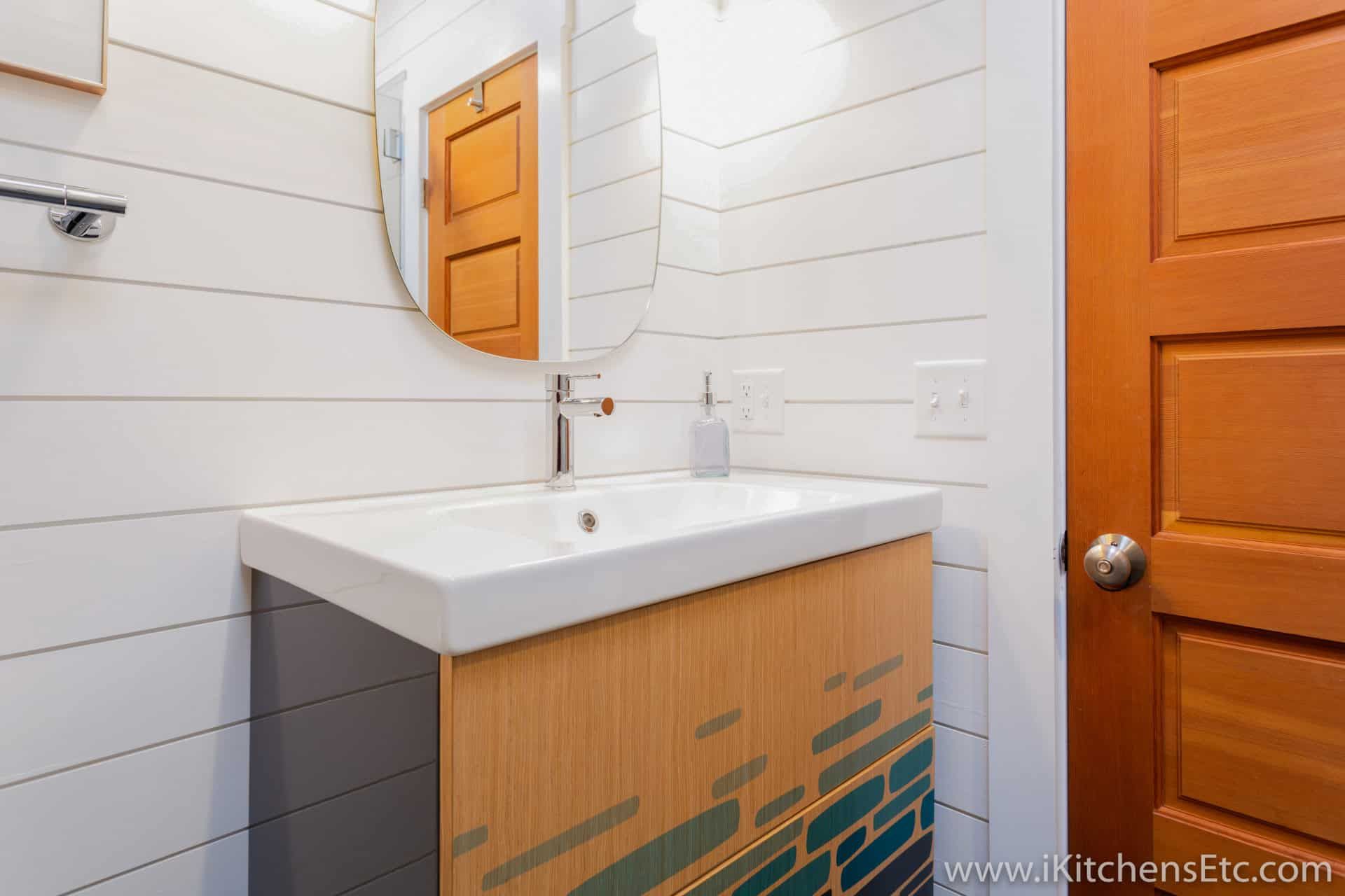 A bathroom with a sink, mirror and door.