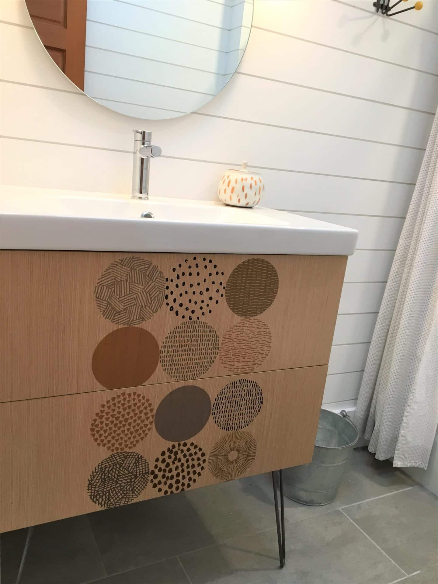 A bathroom with a sink and a mirror and a wooden cabinet with circles on it