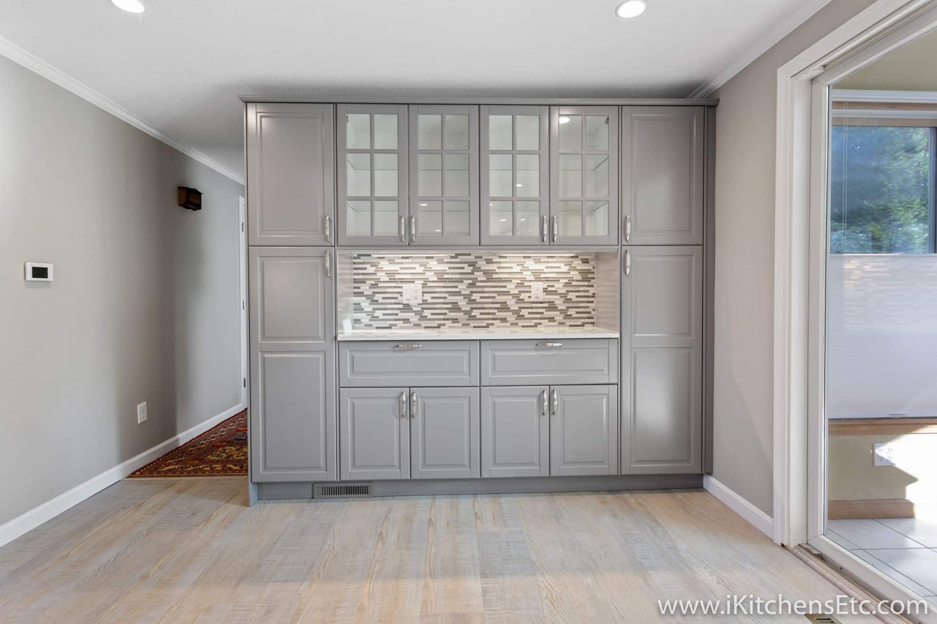 A kitchen with gray cabinets and white counter tops