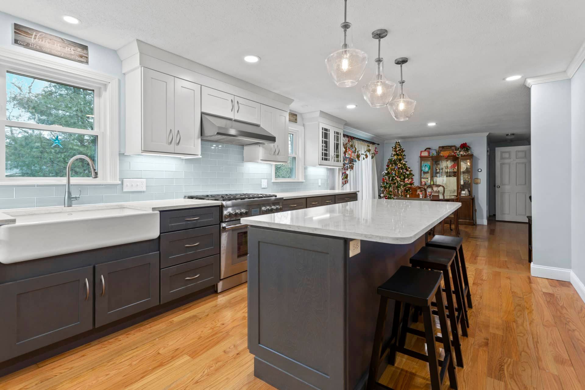 A kitchen with a large island and a christmas tree in the background.