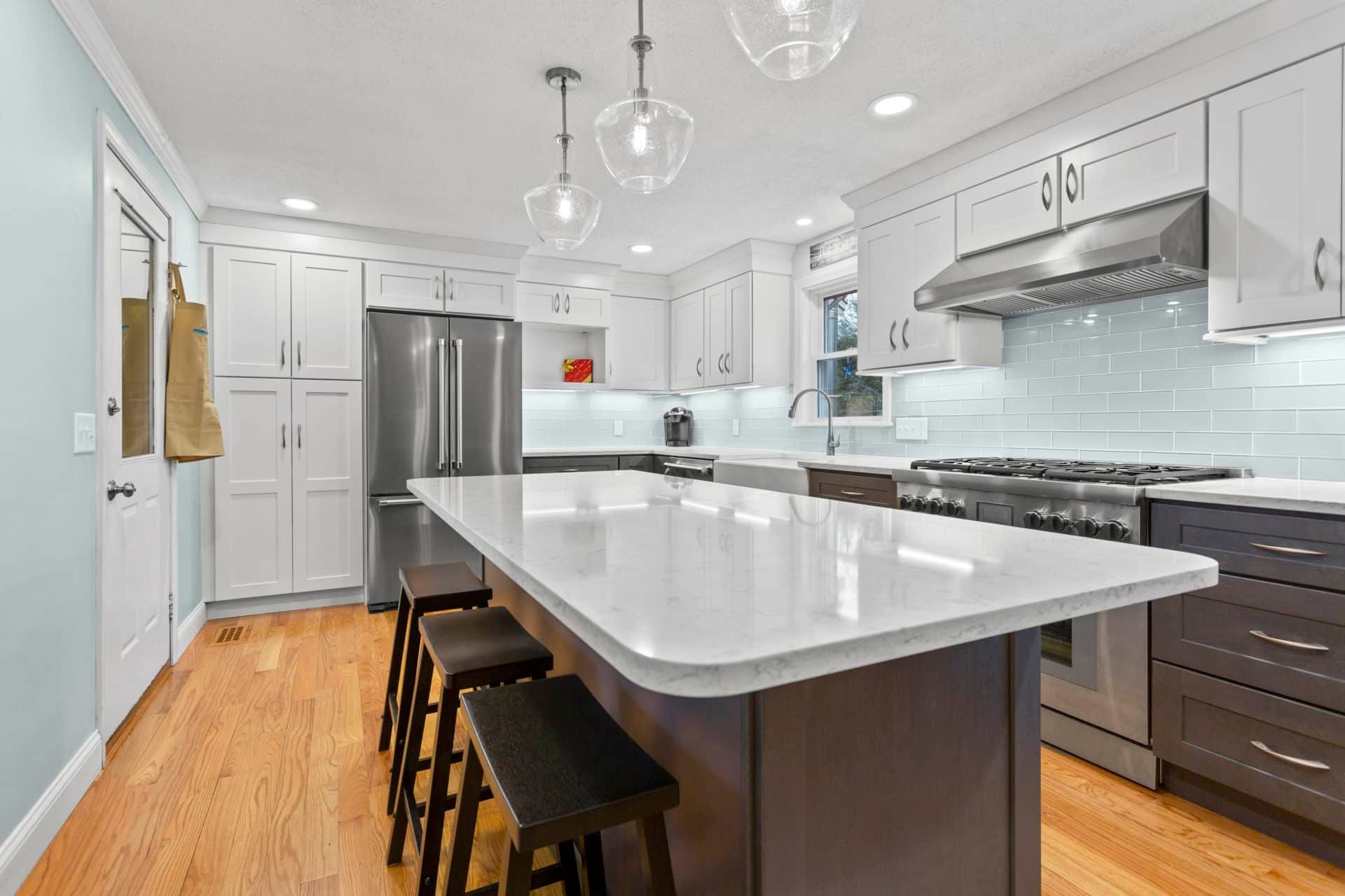 A kitchen with white cabinets, stainless steel appliances, and a large island.