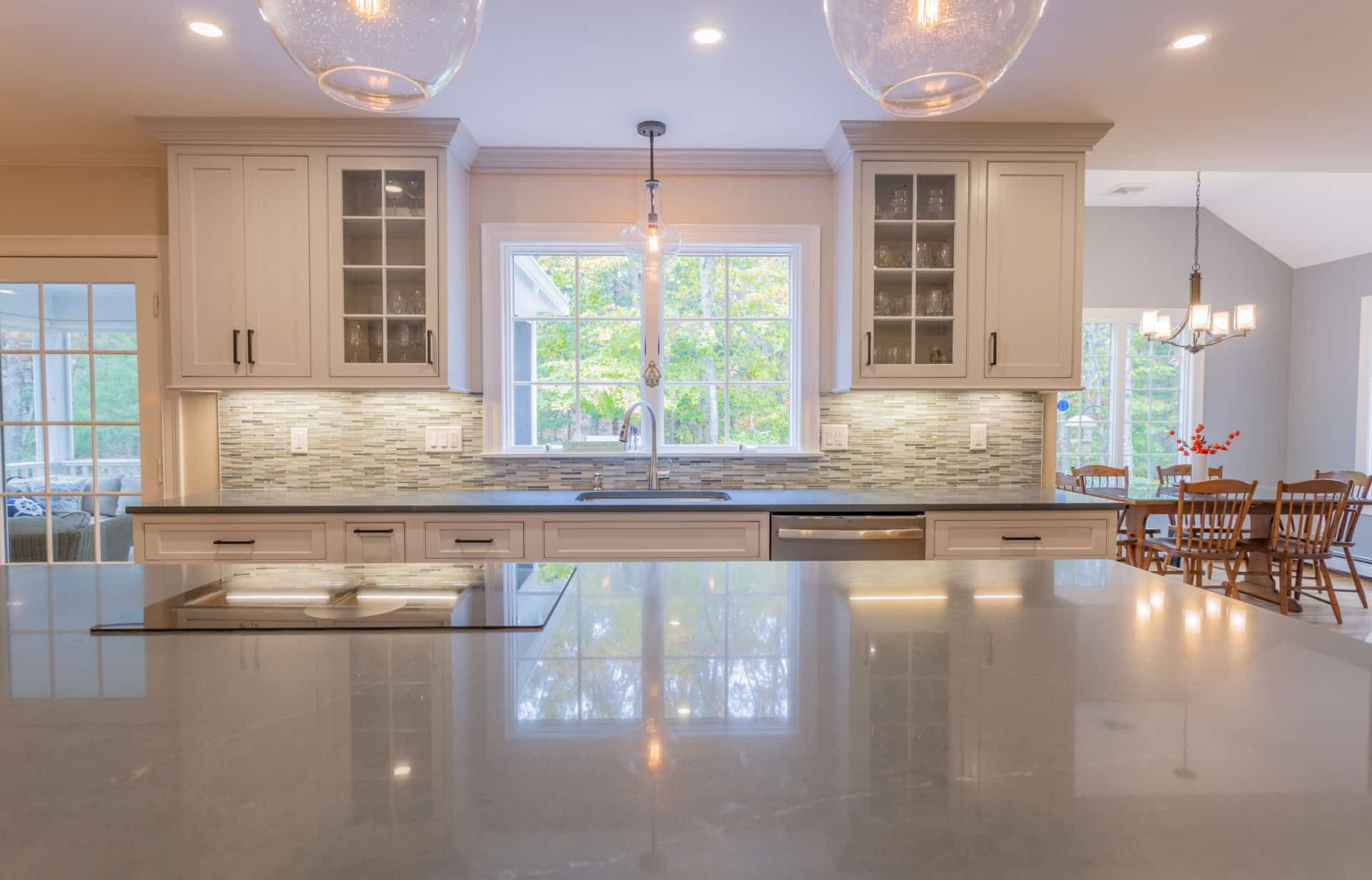 A kitchen with white cabinets, black counter tops, a sink, and a stove top oven.