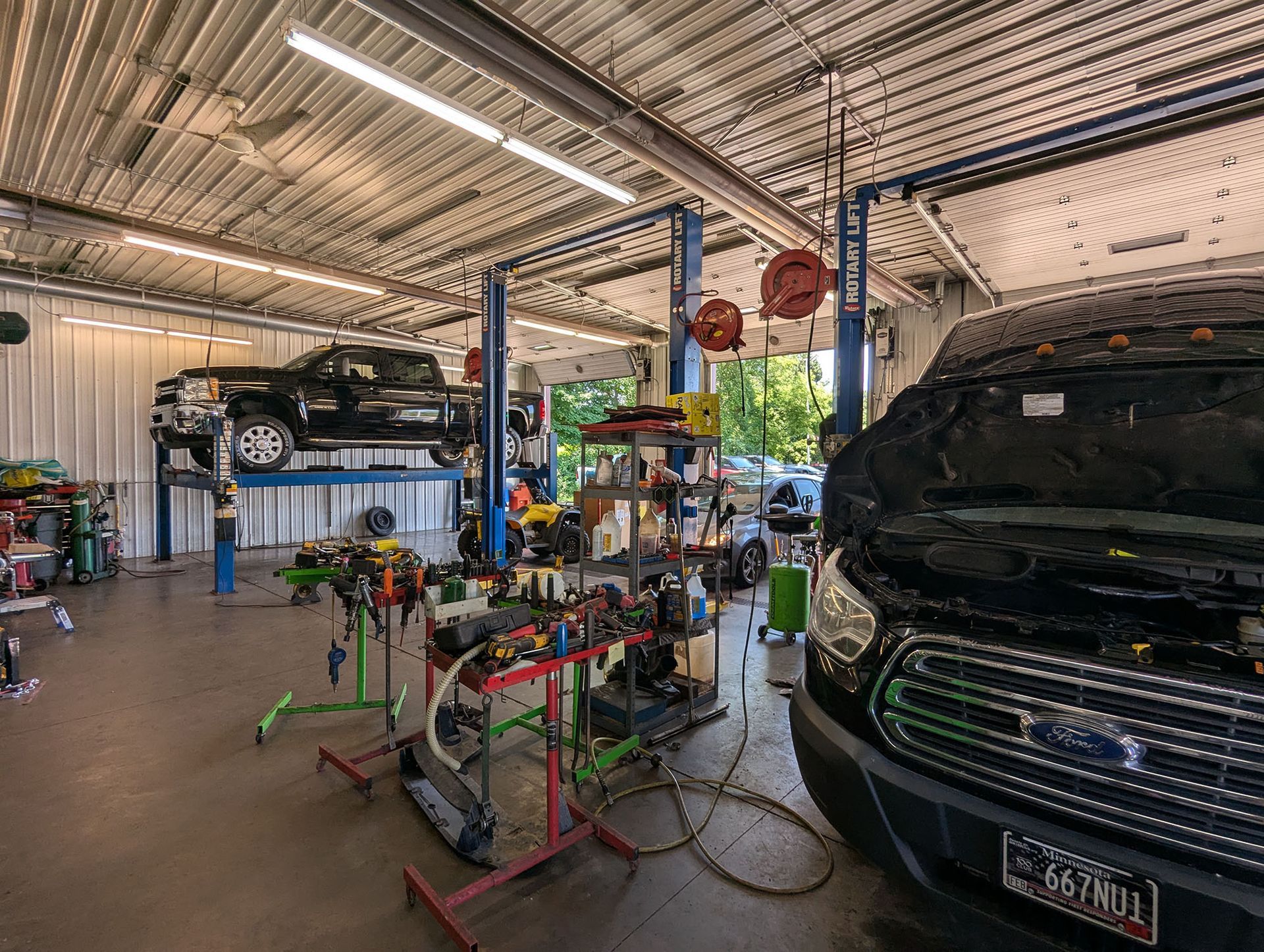 A black volkswagen tiguan with a damaged front end is sitting in a garage.