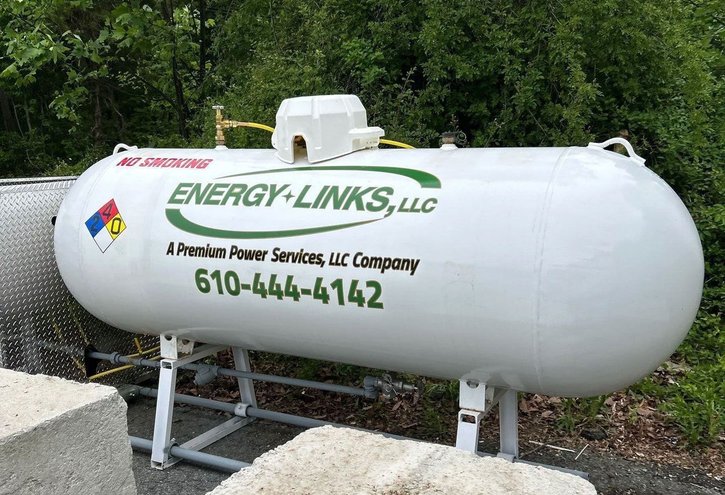 White propane tank labeled “ENERGY-LINKS, LLC” with phone number, mounted outdoors