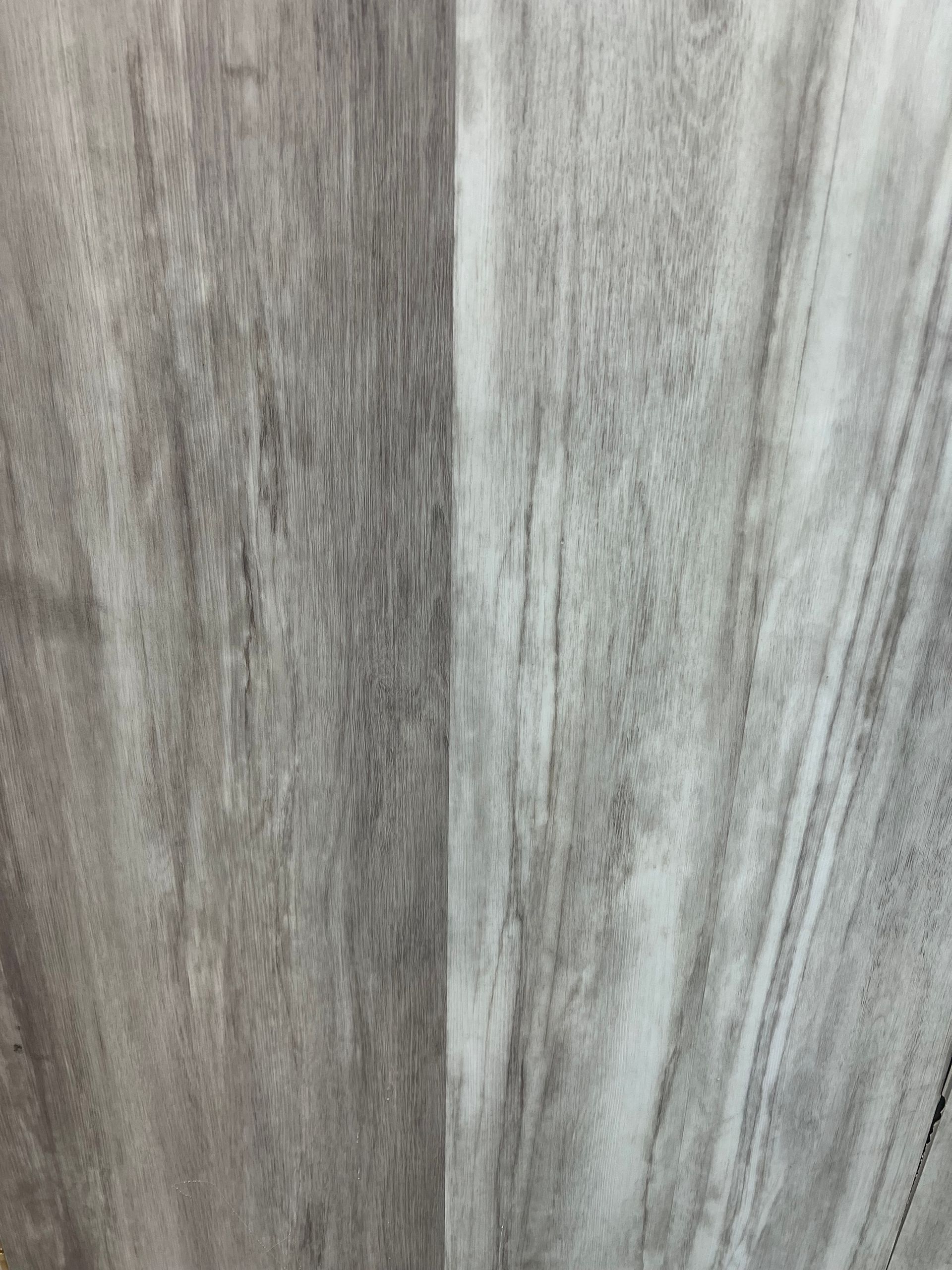 A vertical close-up of light gray wood-look vinyl planks with linear wood grain patterns.