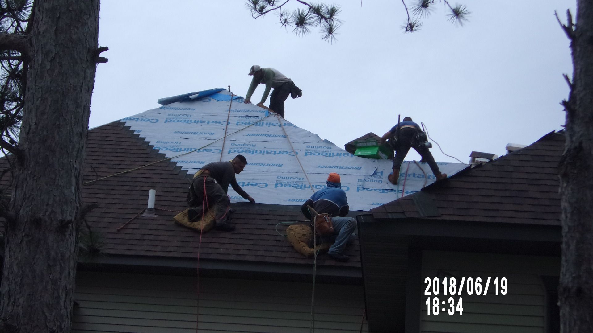 A group of men are working on the roof of a house.