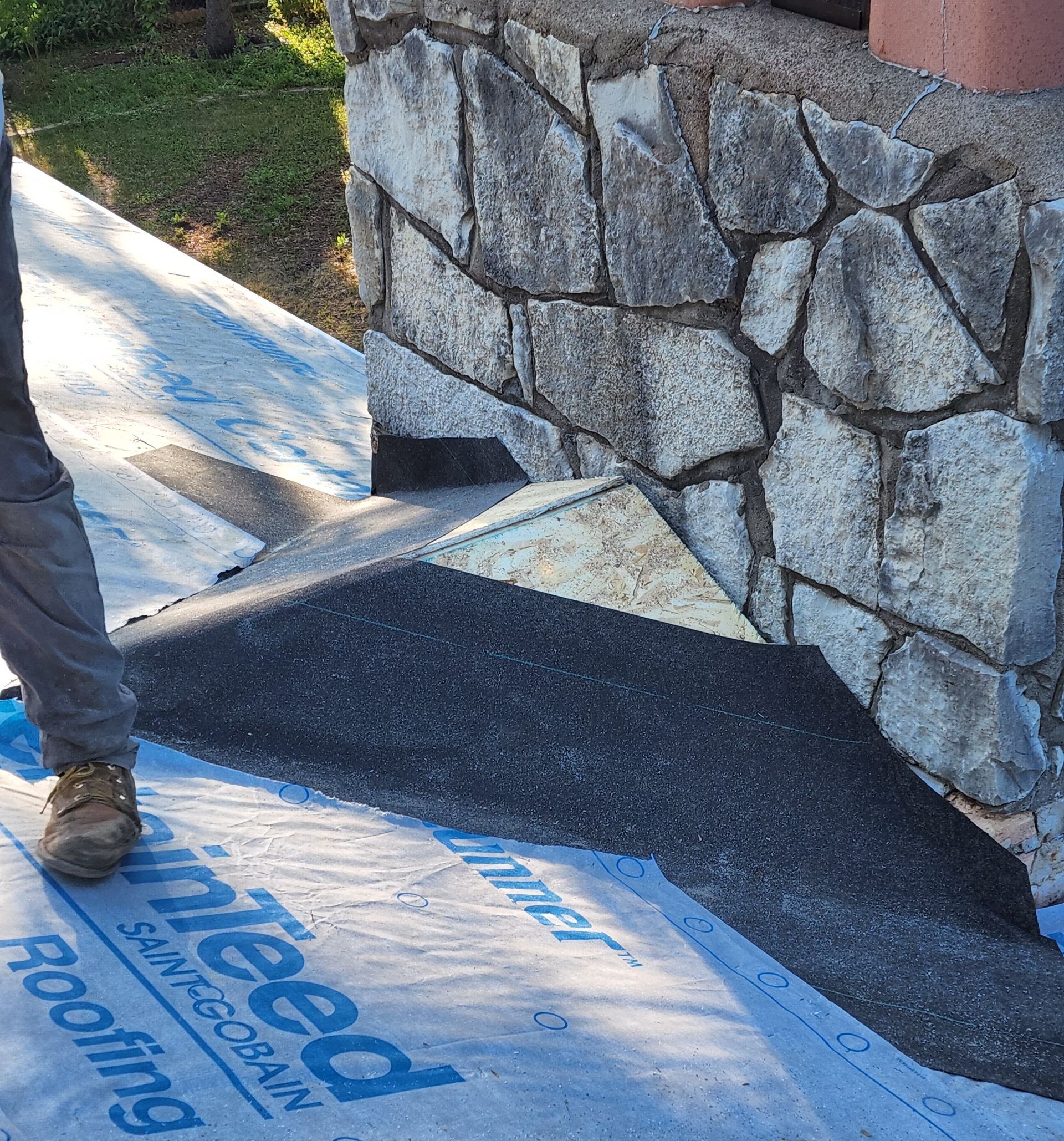 A man is standing next to a stone wall on a roof.