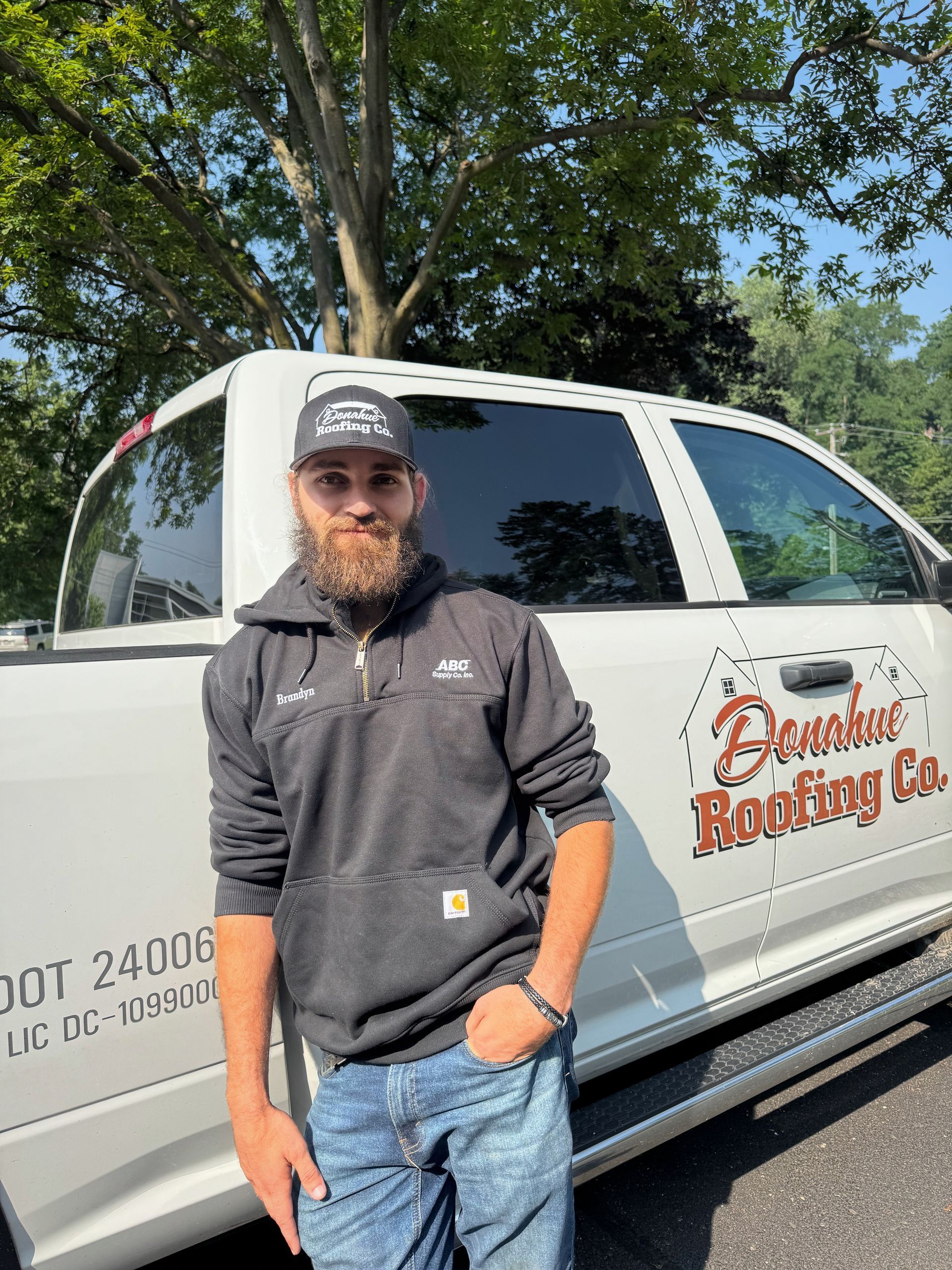 A man with a beard is standing in front of a white truck.