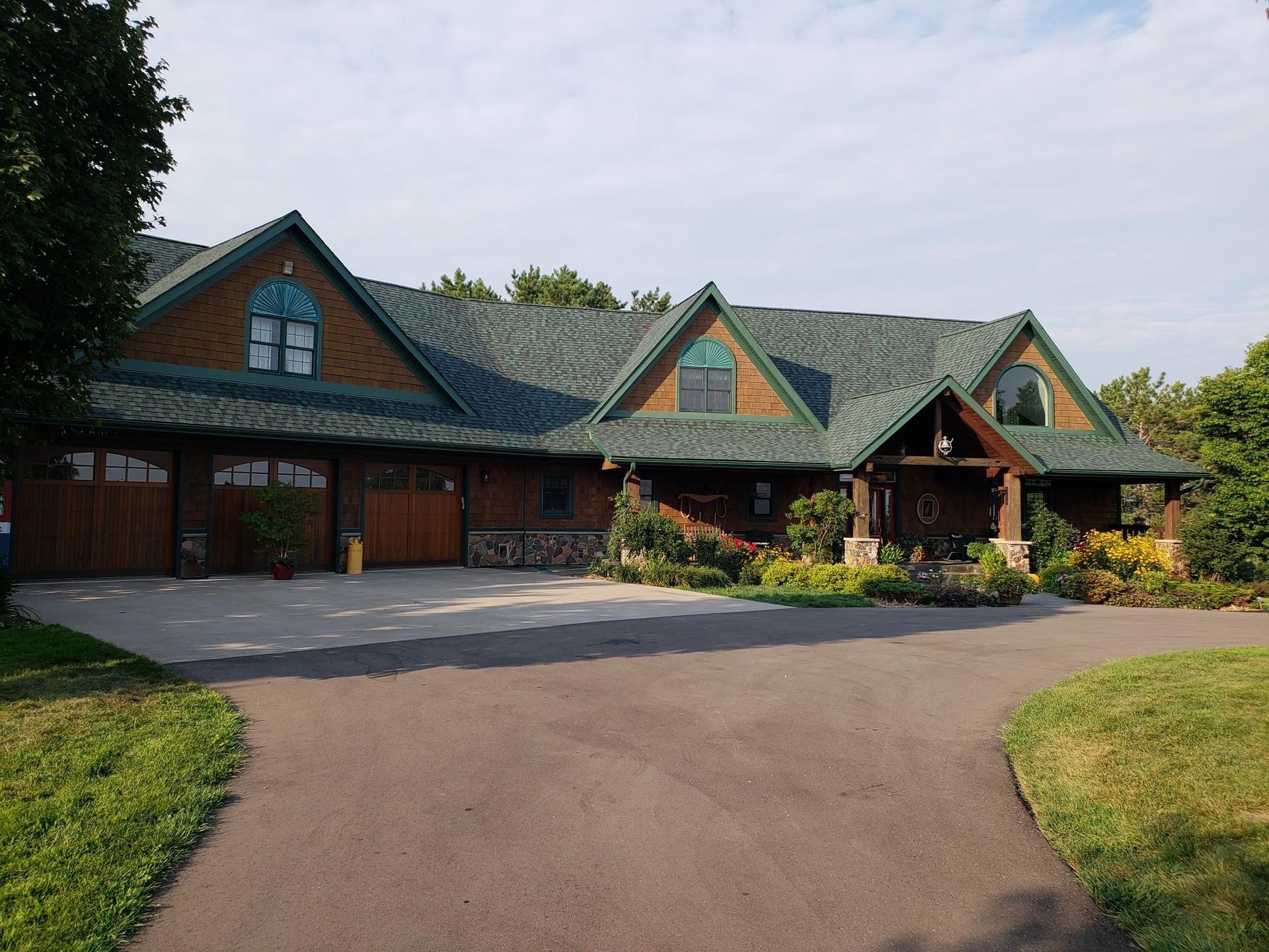 A large house with a green roof and a driveway