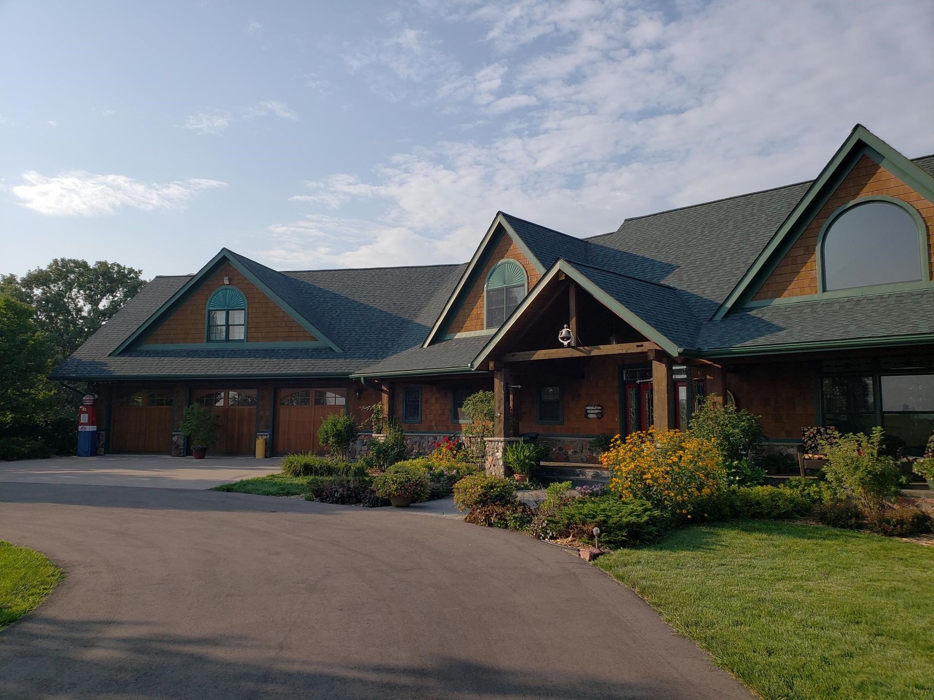 A large house with a green roof and a driveway
