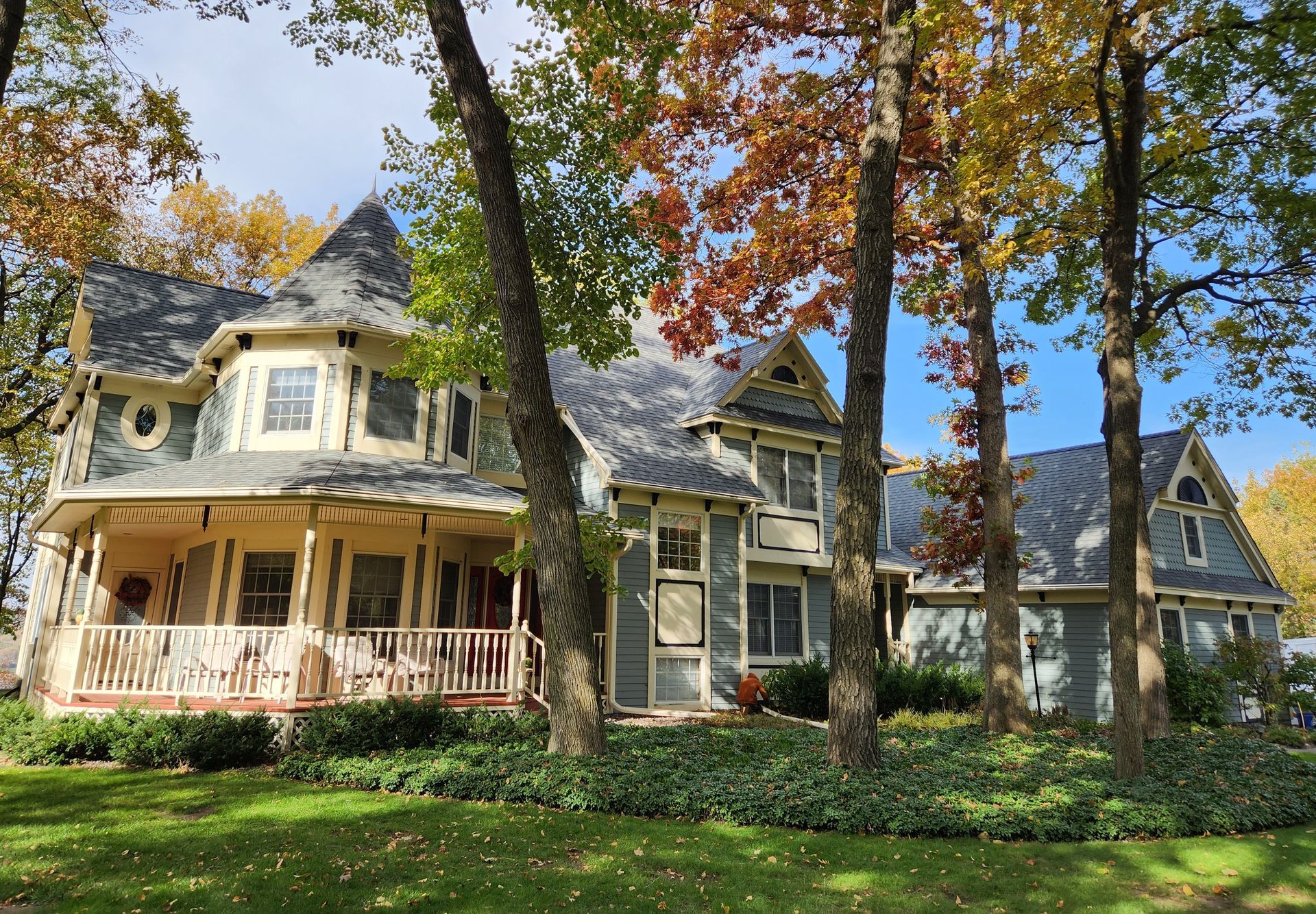 A large house with a large porch surrounded by trees