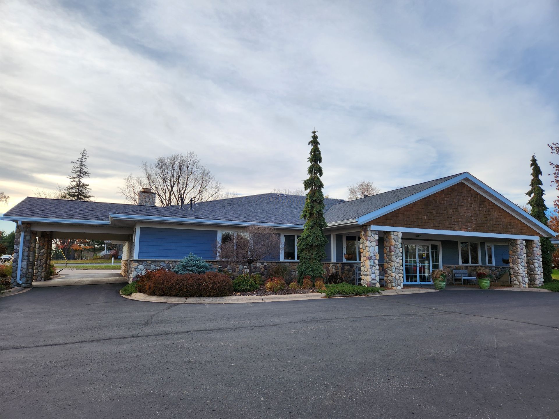 A large blue house with a gray roof and trees in front of it.
