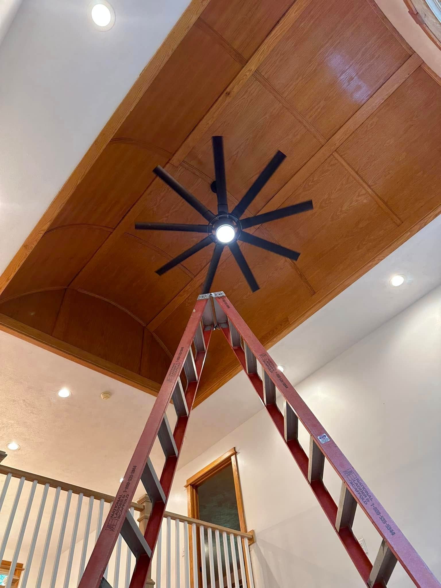A ladder is sitting under a ceiling fan in a room.