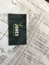 Jones business card on a blueprint-style background, black card with green and white text.