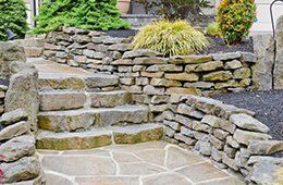 Stone steps and stacked-rock retaining walls in a landscaped garden area