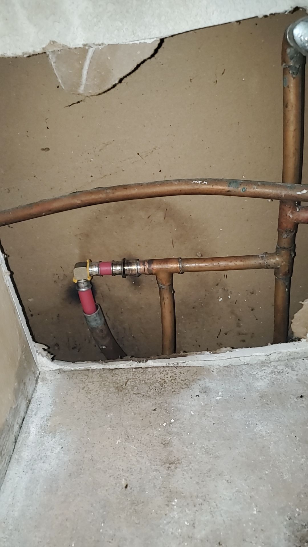 A close up of a copper pipe in a hole in the wall.