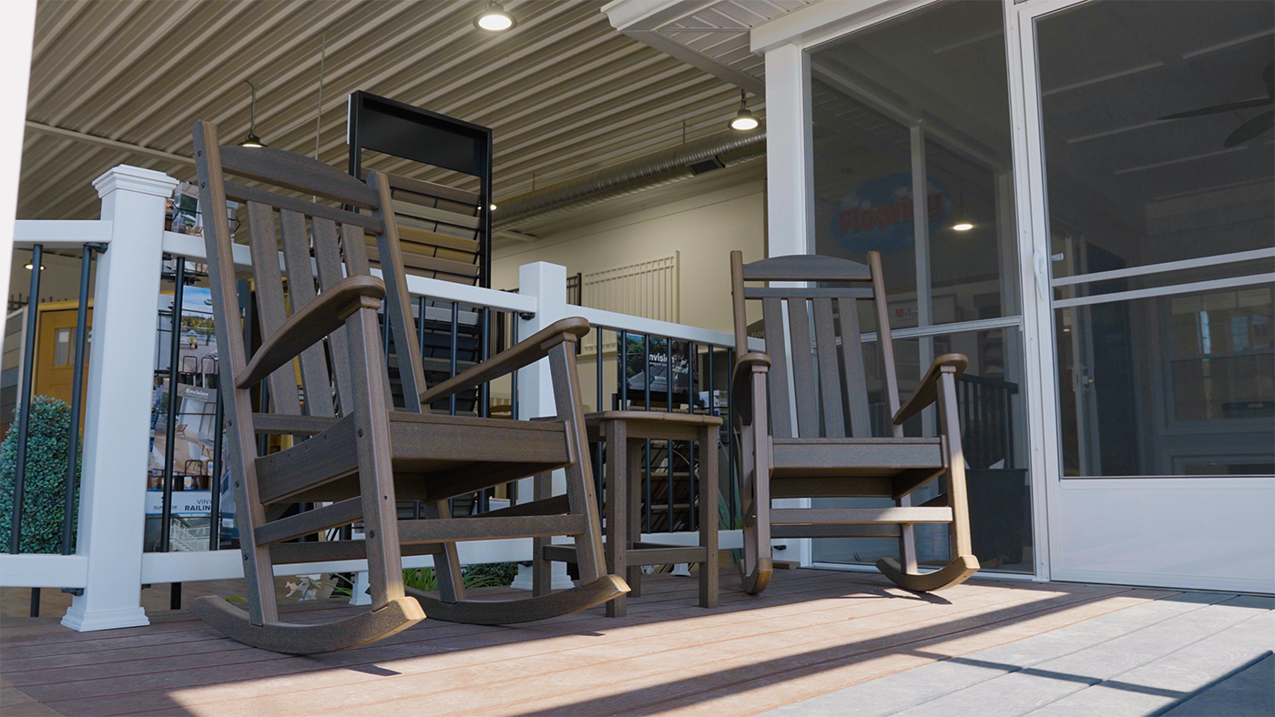 Two rocking chairs are sitting on a patio next to a screened in porch.