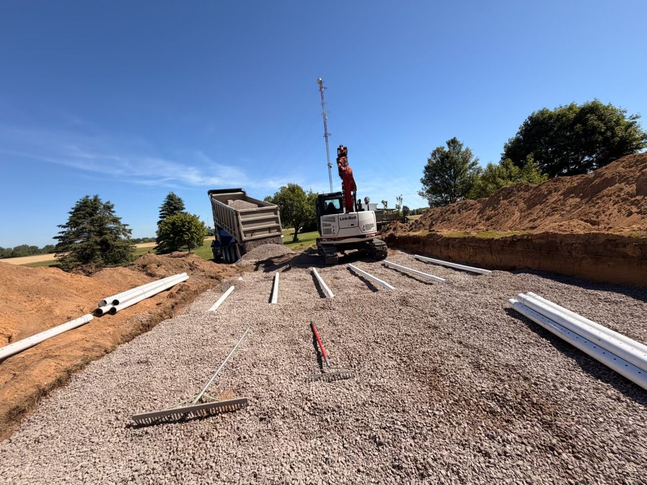 Construction site with crane truck and gravel road under a clear blue sky