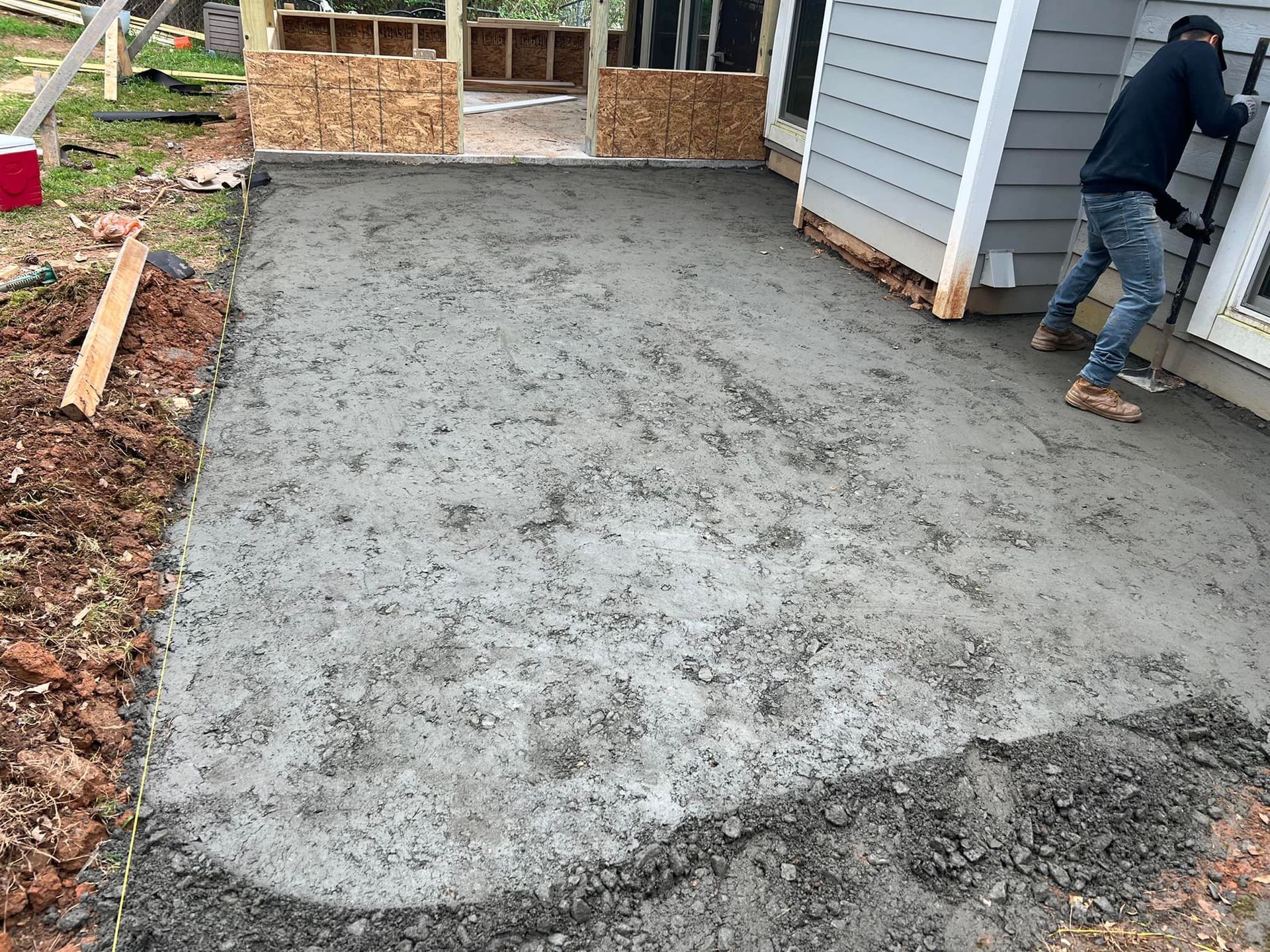 Freshly poured concrete patio; a person works next to the building.