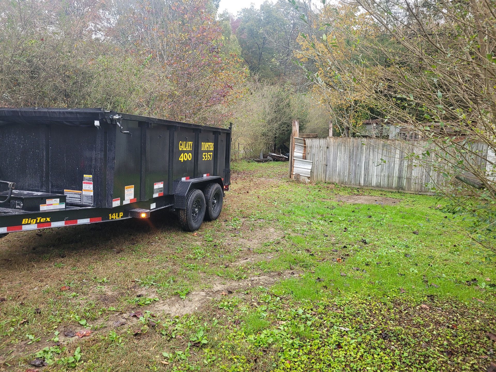 A dumpster trailer is parked in a grassy field.