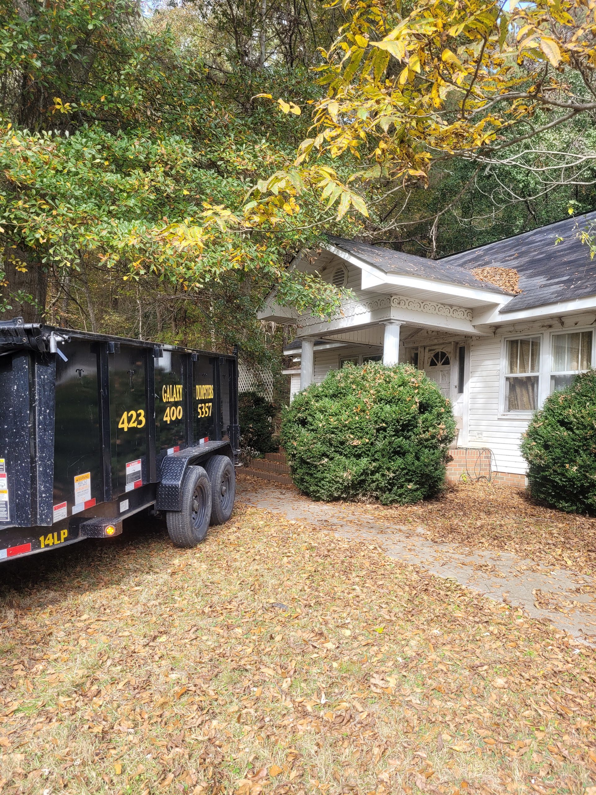 A dumpster is parked in front of a house.