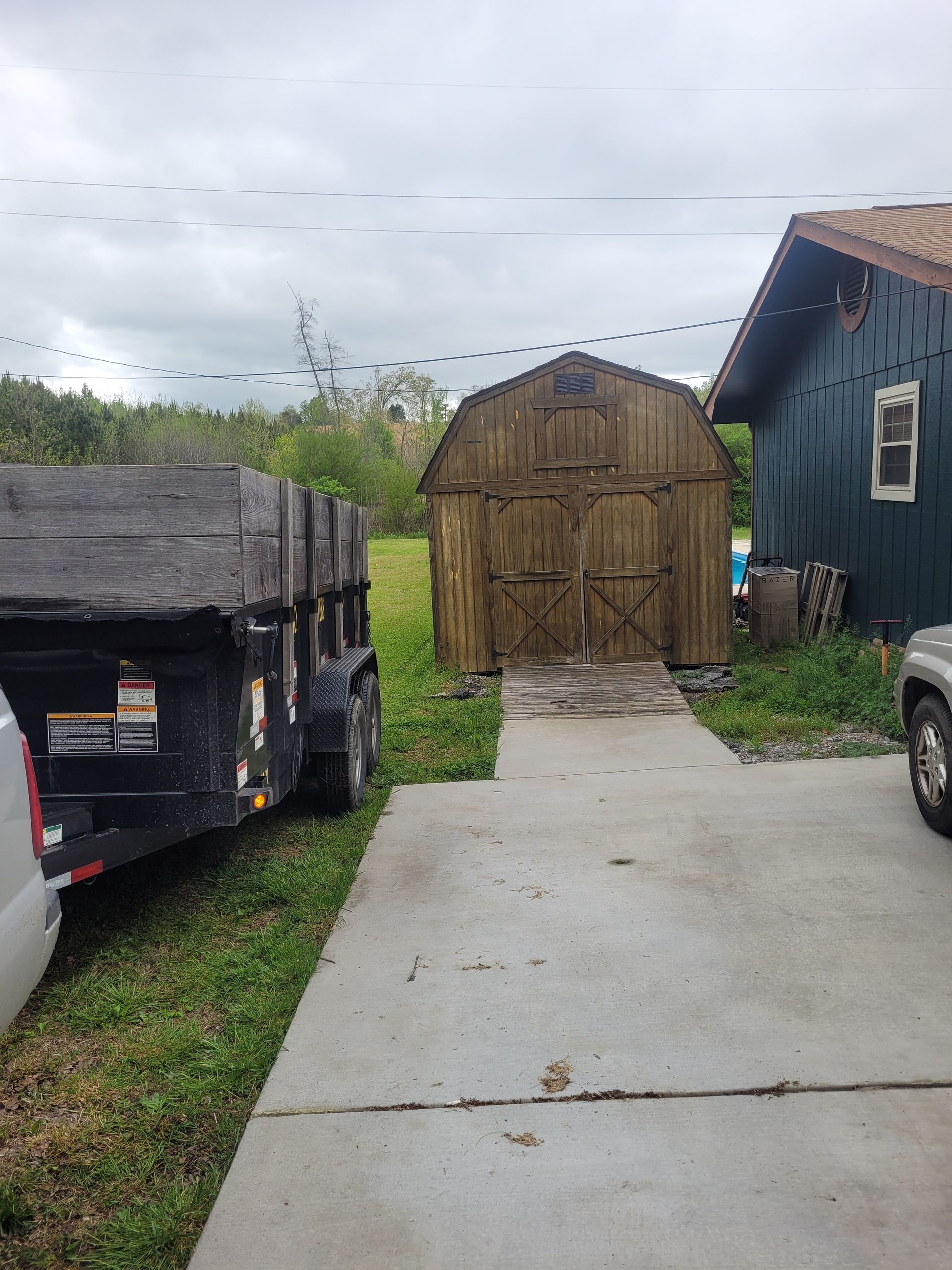 A truck is parked in a driveway next to a barn