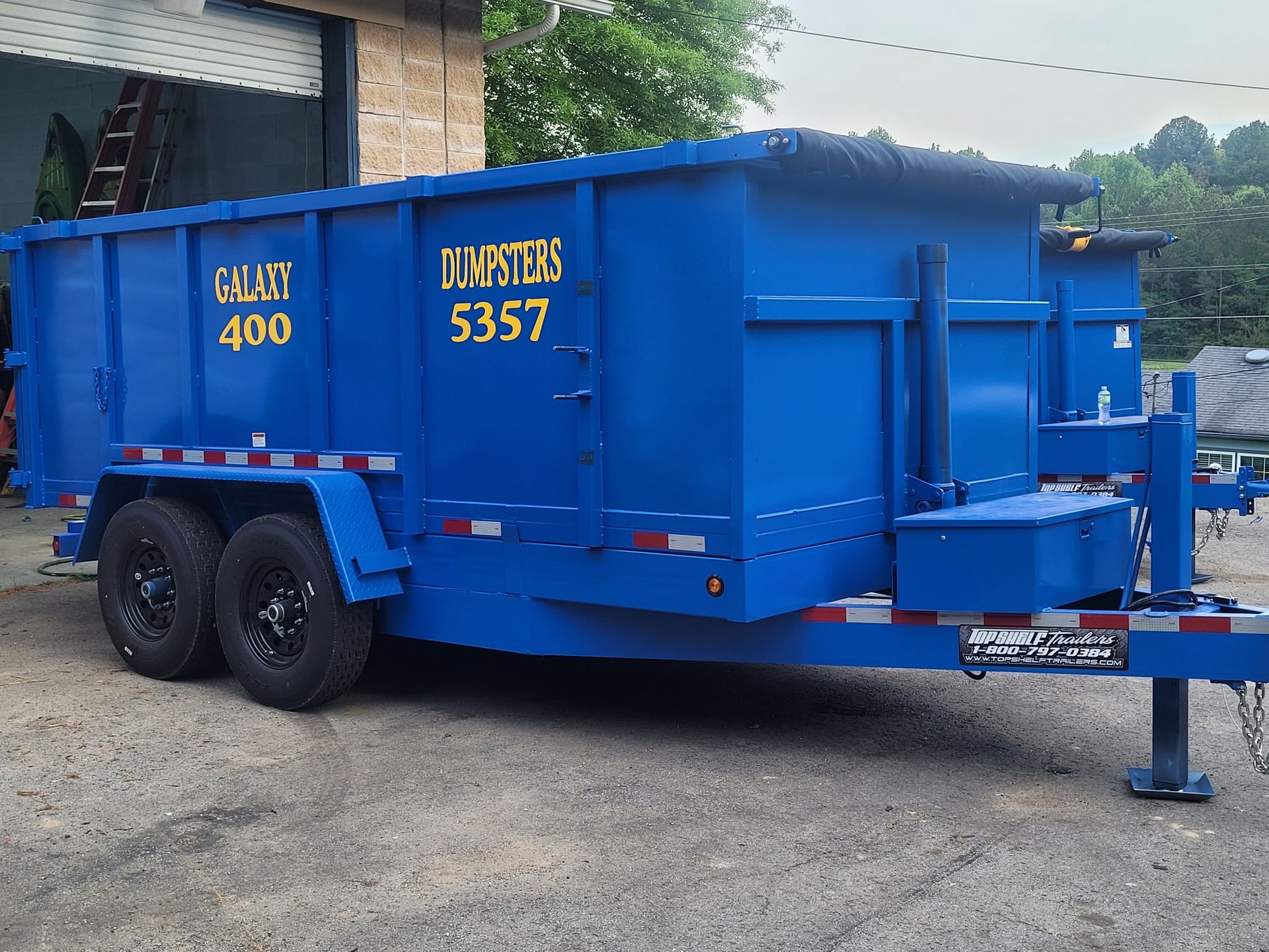 A blue dumpster with the number 5357 on it